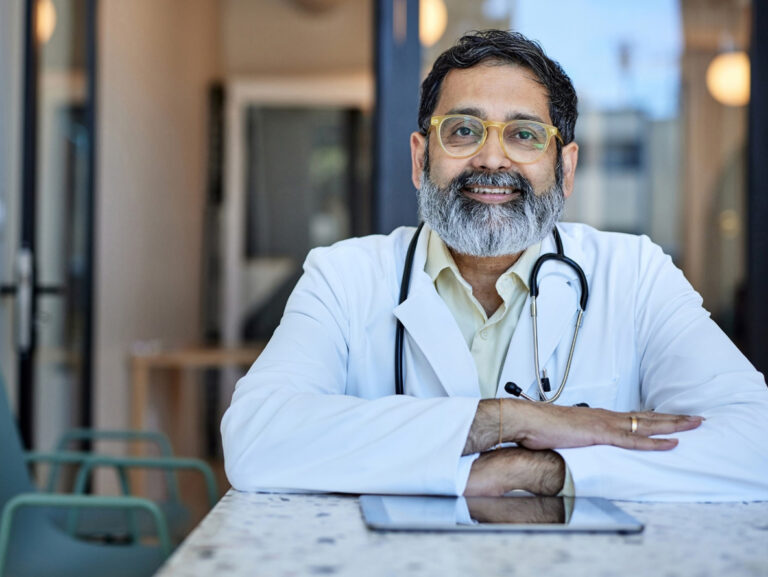 A friendly, local GP smiling across the table