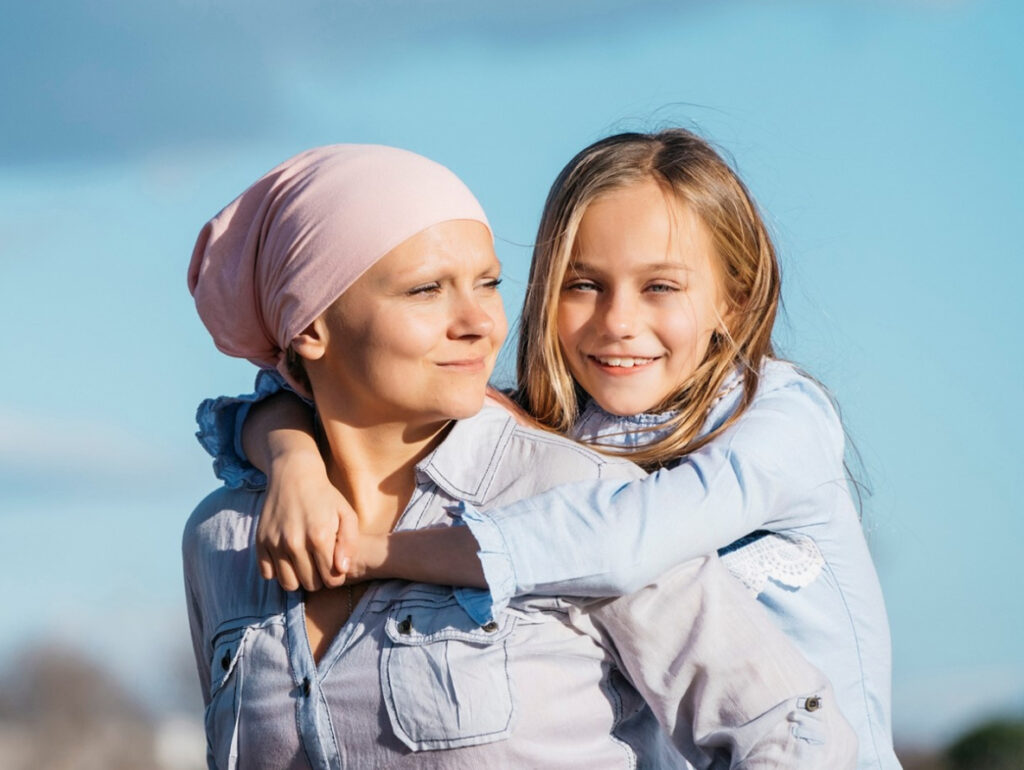 A woman in a bandana carrying a young girl on her back with ease