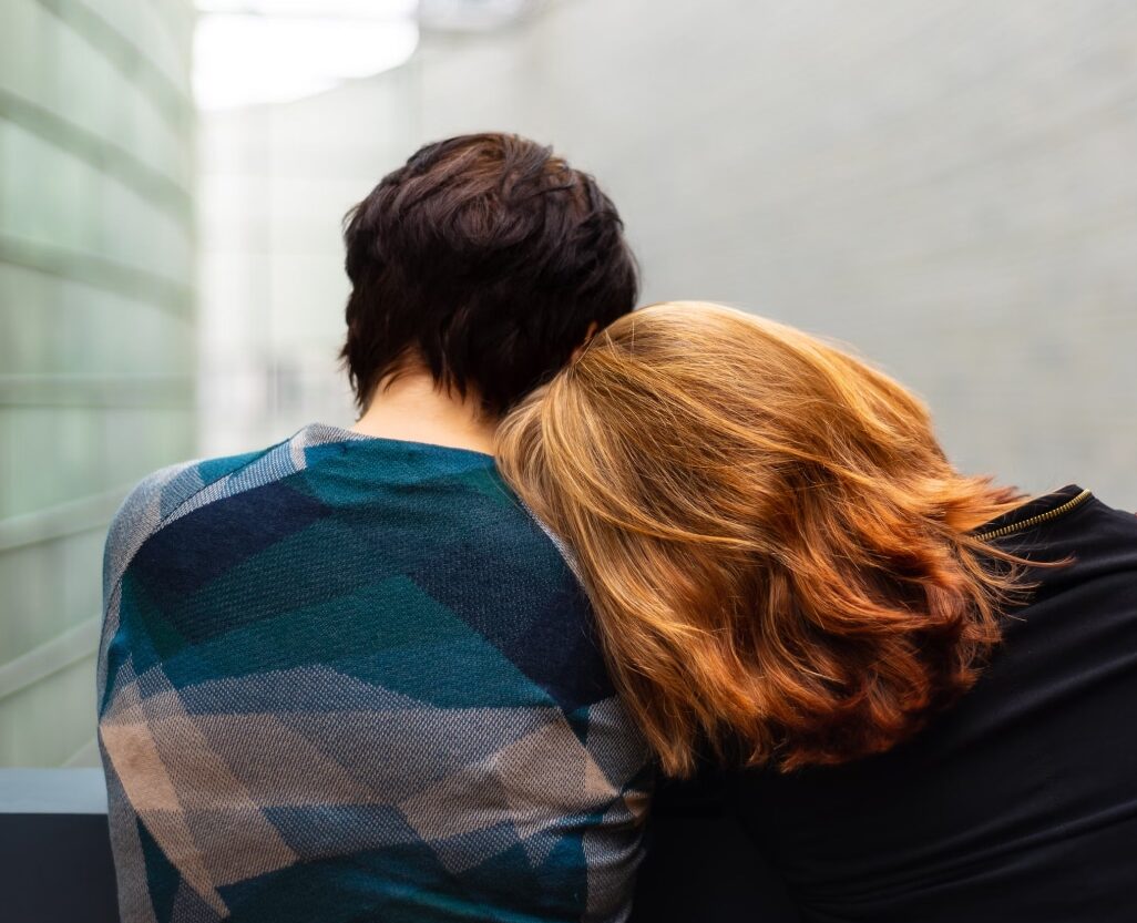 A young woman leaning on the shoulders of a friend for support